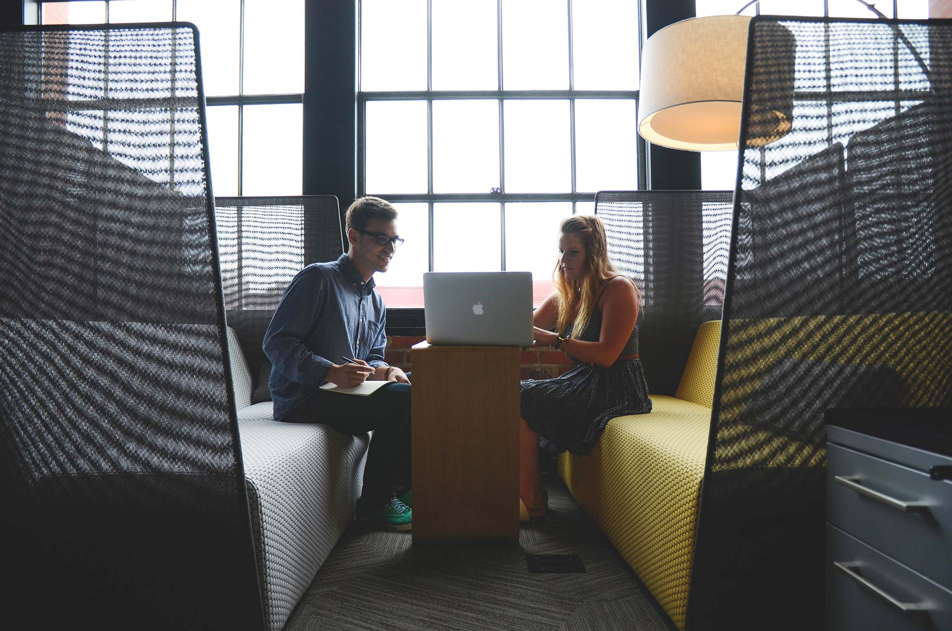 Two professionals discussing work in a modern office booth.