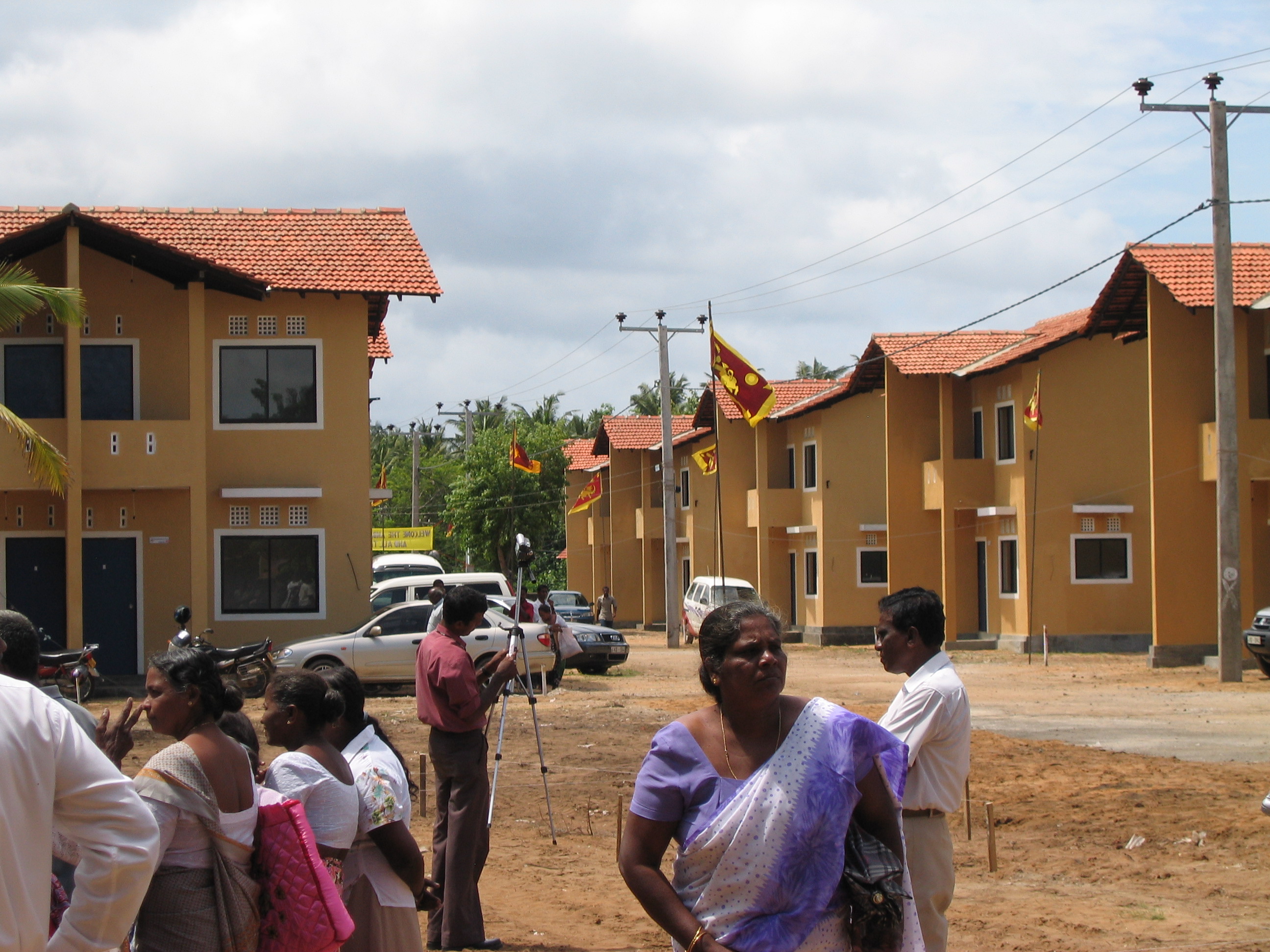 People walking between residential buildings on a cloudy day.