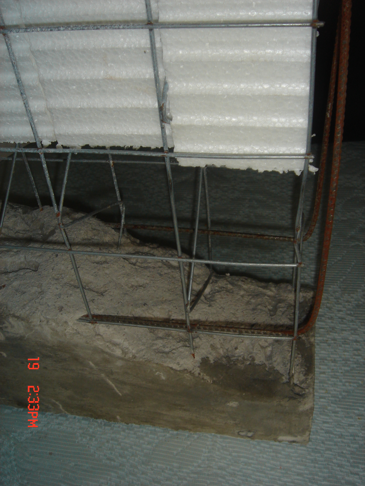 Exposed steel reinforcement bars embedded in concrete at a construction site.