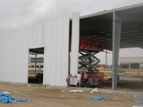 Construction workers installing building wall panel.
