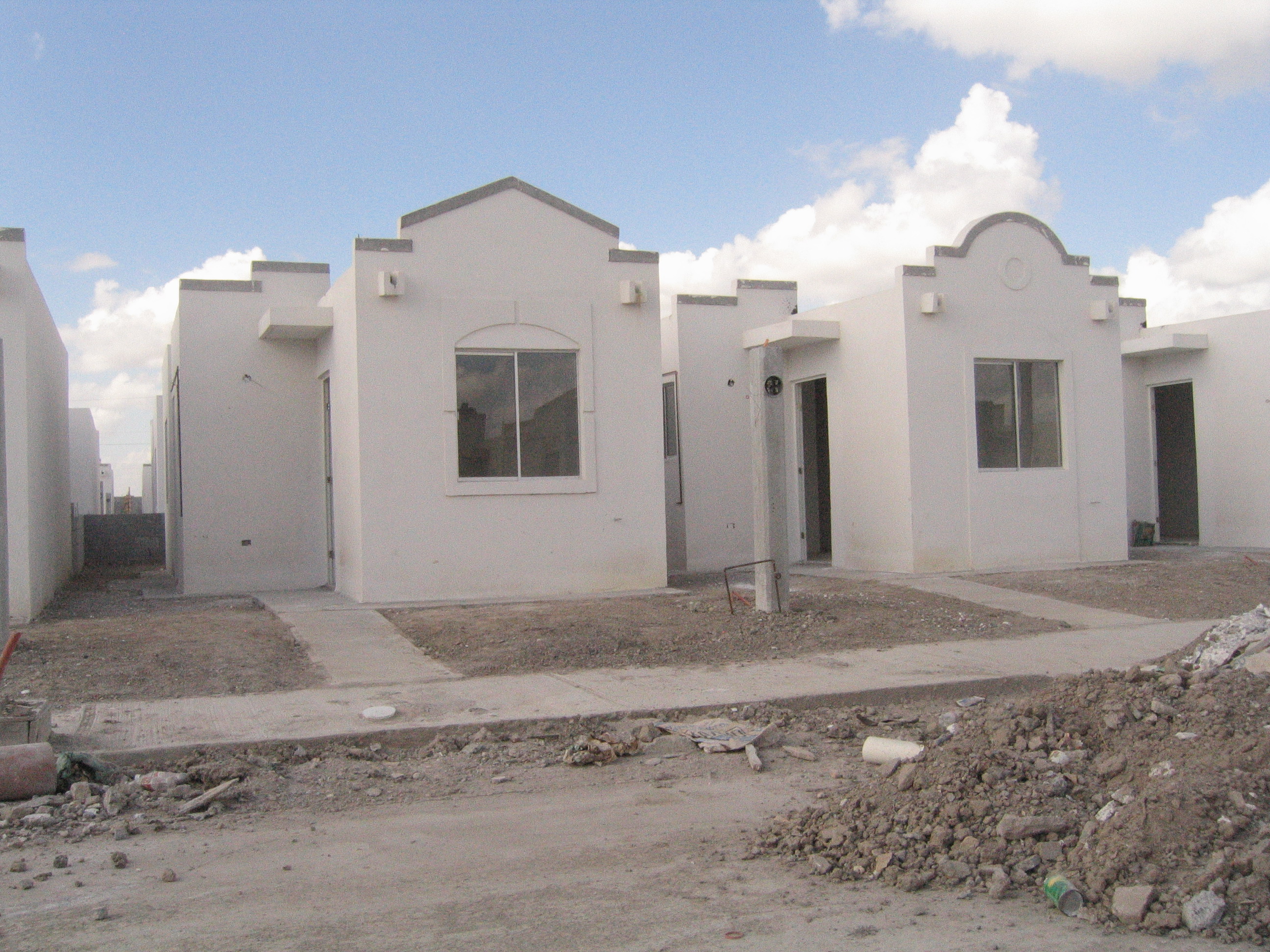 Two small white houses with simple architecture and minimal landscaping.