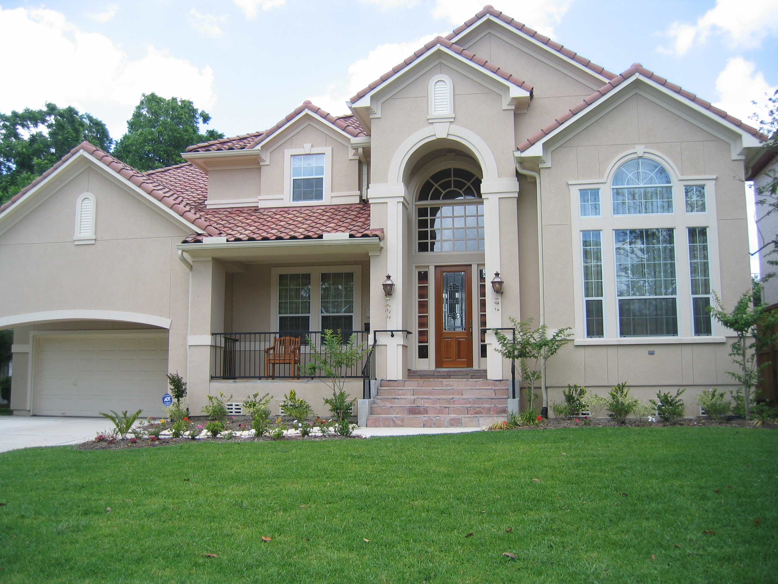 Elegant two-story house with beige exterior and arched entrance.