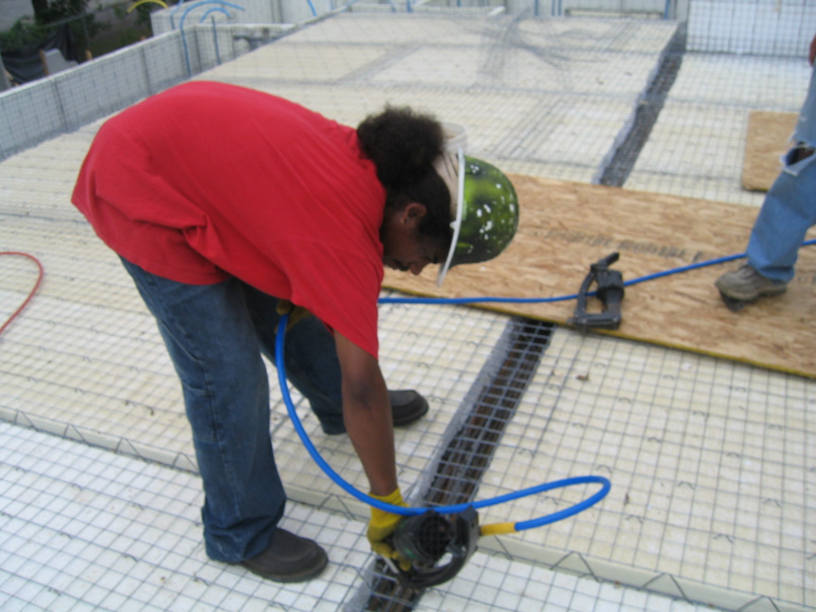 Worker using a tool to secure metal rebar on a construction site.