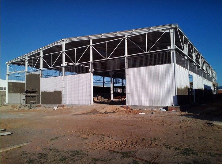 Large industrial building under construction, clear sky.
