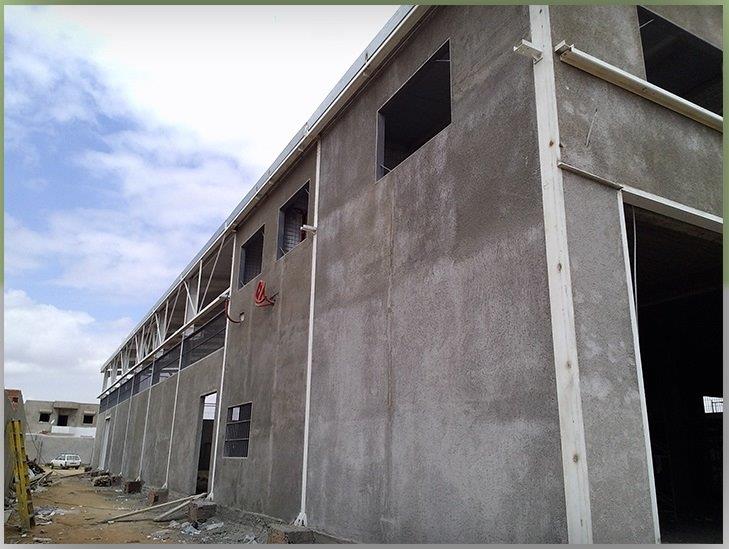 Large industrial building under construction, cloudy sky.
