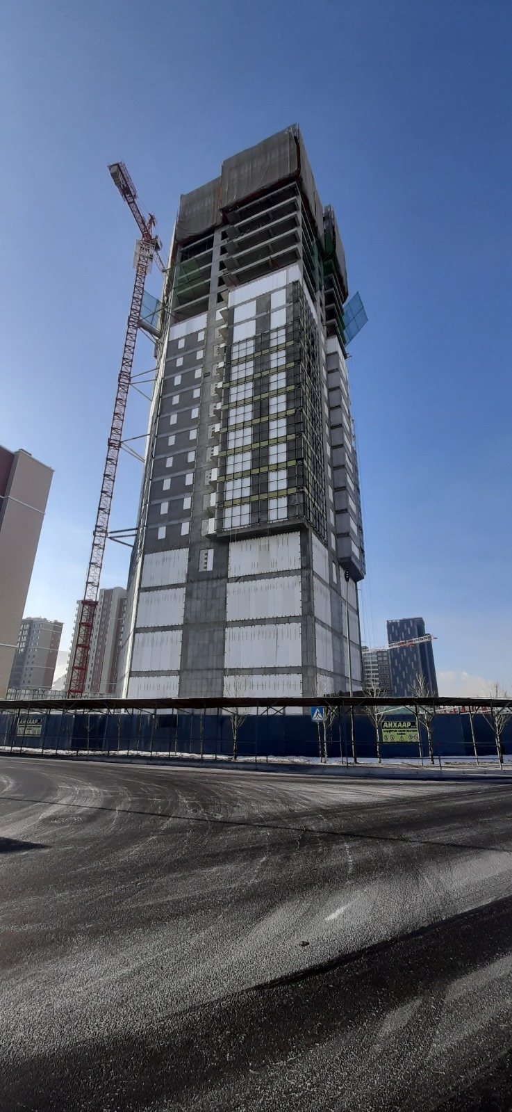 Skyscraper under construction with crane nearby.