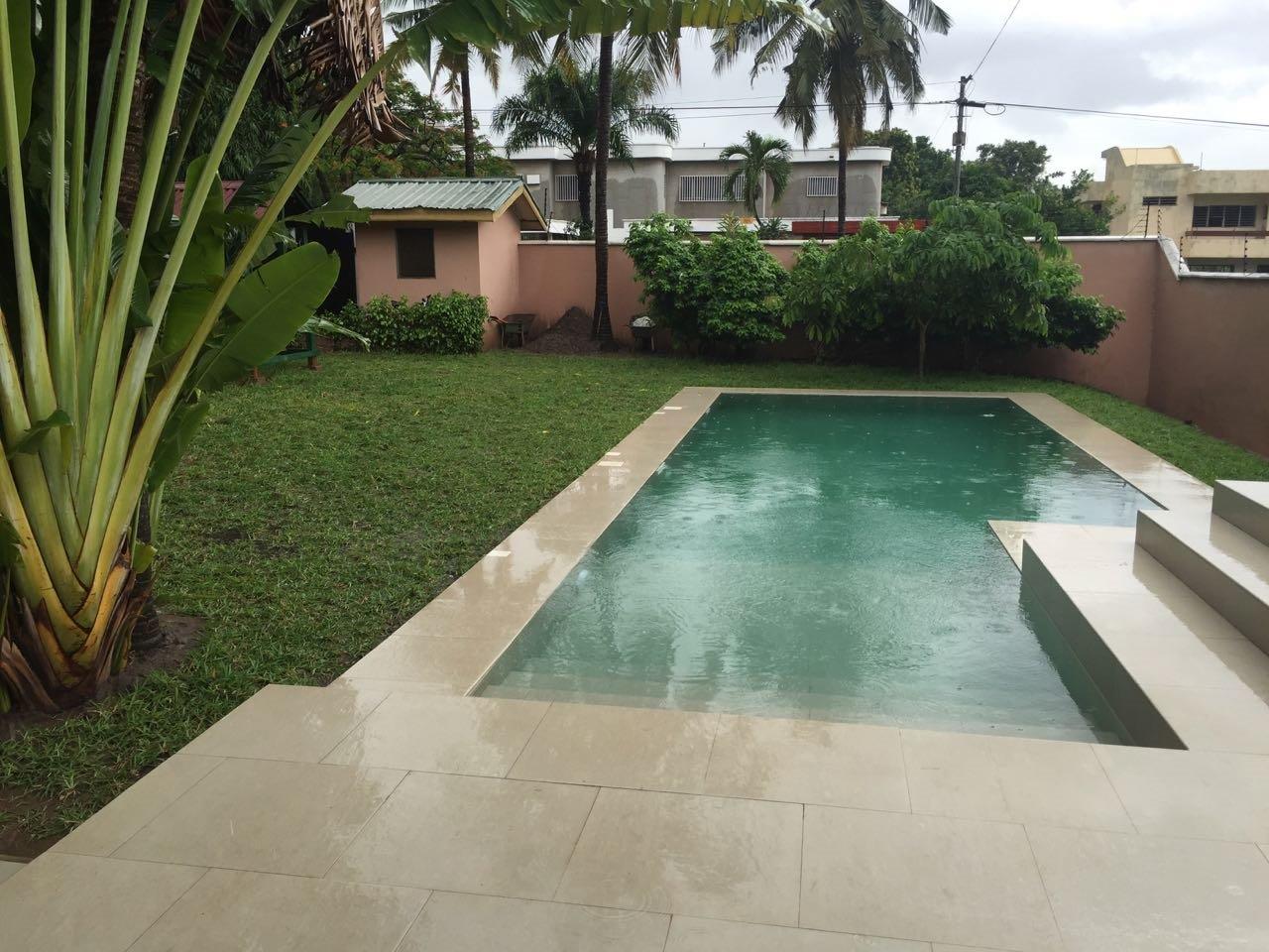 Backyard pool with surrounding greenery and trees.